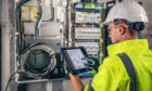 technician working on a switchboard with fuses, uses a tablet for an Ex inspection