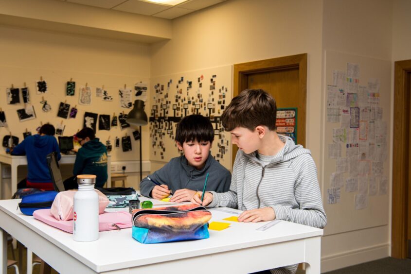 students gather at tables in pairs for their schoolwork