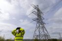 A ScottishPower employee standing near grid transmission infrastructure.