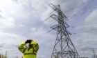 A ScottishPower employee standing near grid transmission infrastructure.
