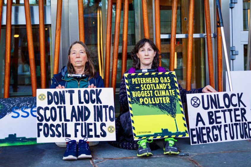 Extinction Rebellion campaigners locked themselves to the Scottish Parliament.