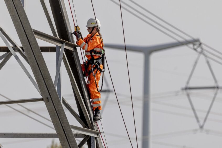 A National Grid technician climbing an electricity pylon.