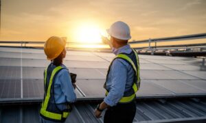 Engineers look at sun in the horizon after installing solar panels, increasing renewable energy capacity as reported in DNV UK ETO