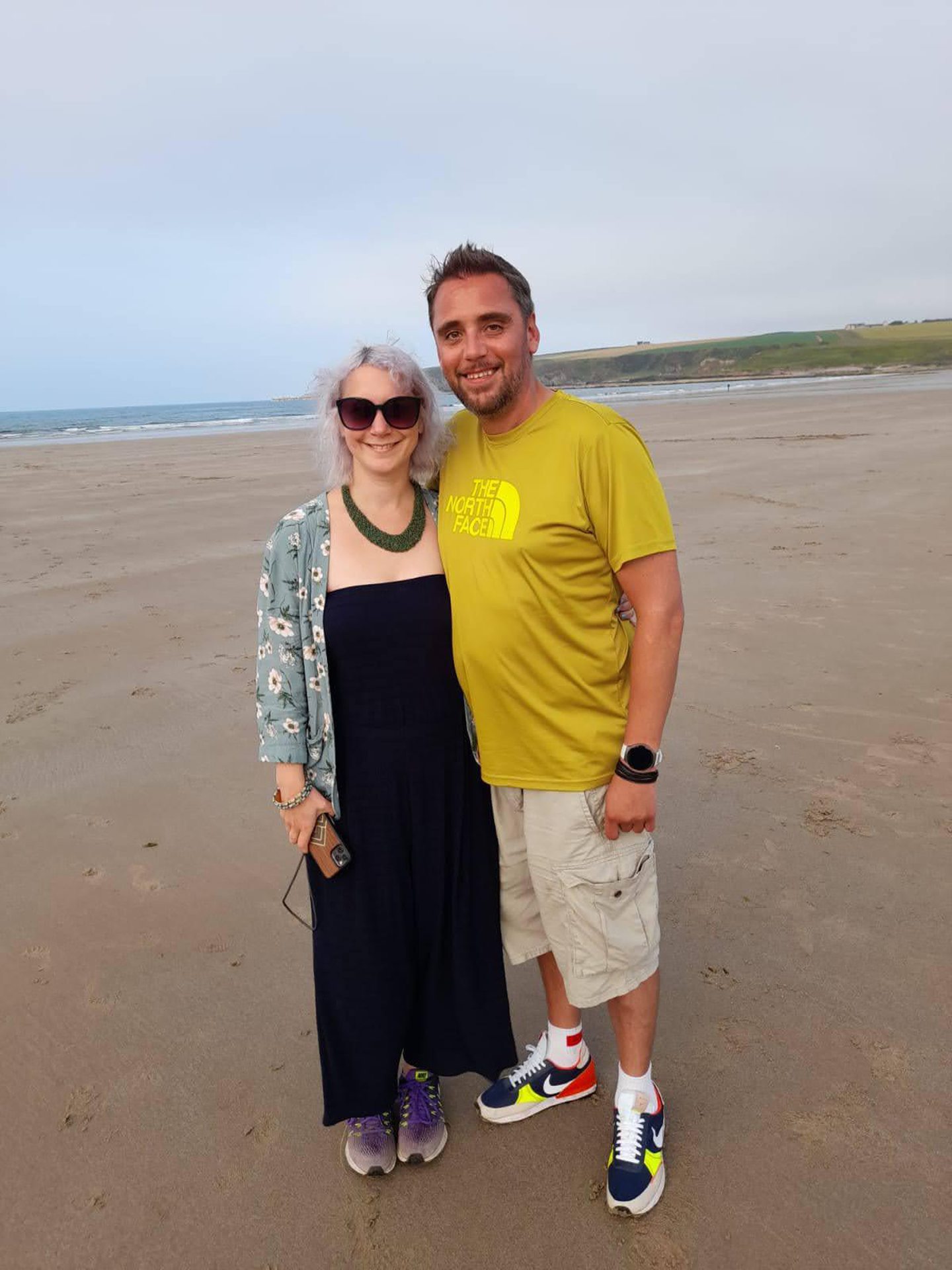 Bryony Revell and Allan Basil standing together on a beach.