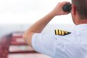 A naval officer looking through a pair of binoculars.