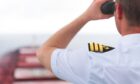 A naval officer looking through a pair of binoculars.