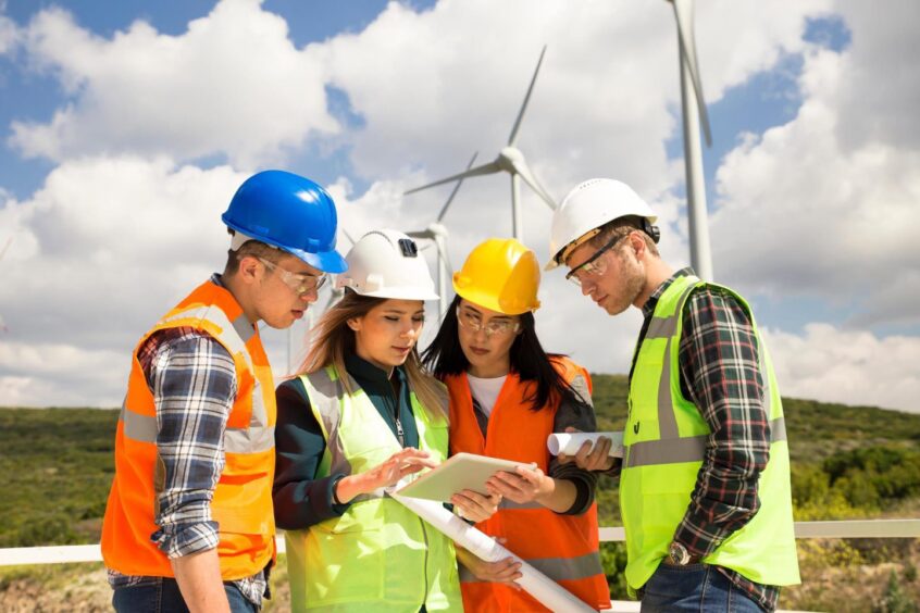 Young engineers and workers having a meeting at wind farm.