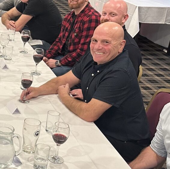 Mick Gillespie at a dinner with a glass of red wine.