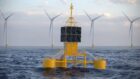 Telecommunications equipment mounted on a floating buoy with offshore wind turbines in the background.