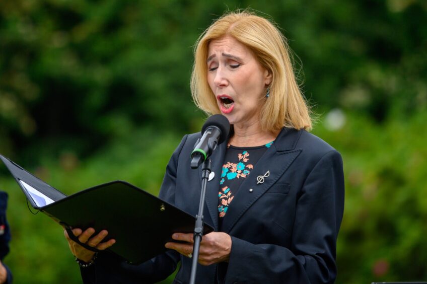 Moira Docherty sings from a music folder during the 2025 Piper Alpha remembrance service in Aberdeen’s Hazlehead Park.