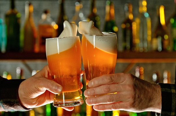 Two men toasting each other with a glass of beer