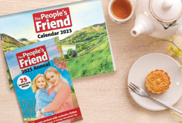 Flatlay of The People's Friend calendar and annual next to tea and biscuit