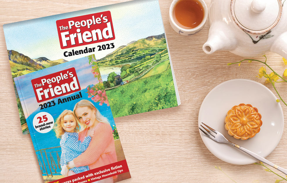 Flatlay of The People's Friend calendar and annual next to tea and biscuit