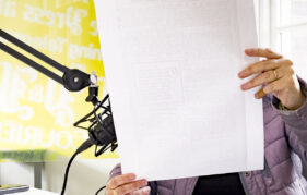 Podcast studio reading from paper into microphone