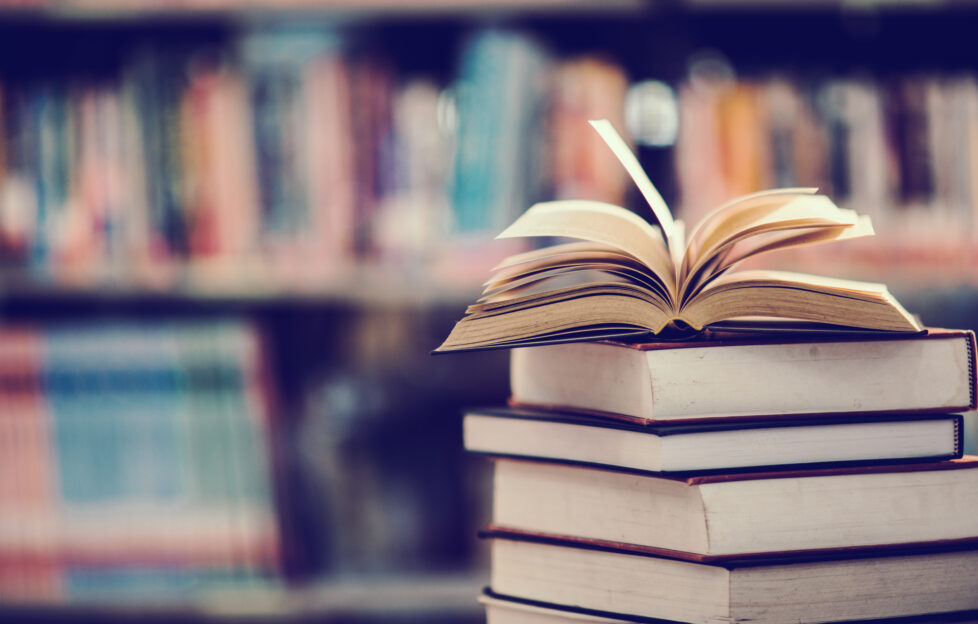 Stack of books against a bookshelf backdrop