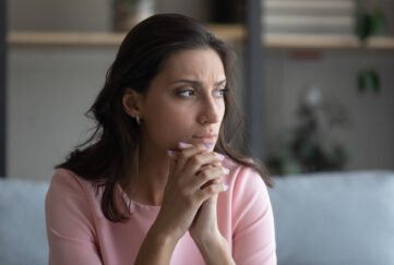 Worried young woman holding hangs together