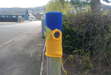 Yarn bombing art in support of Ukraine on wooden post