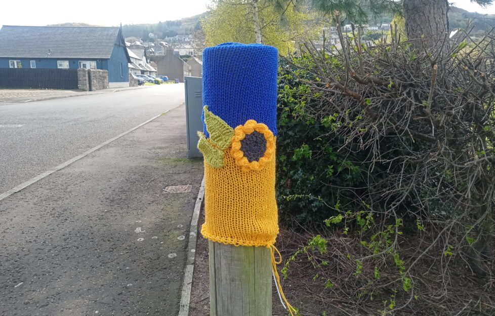 Yarn bombing art in support of Ukraine on wooden post