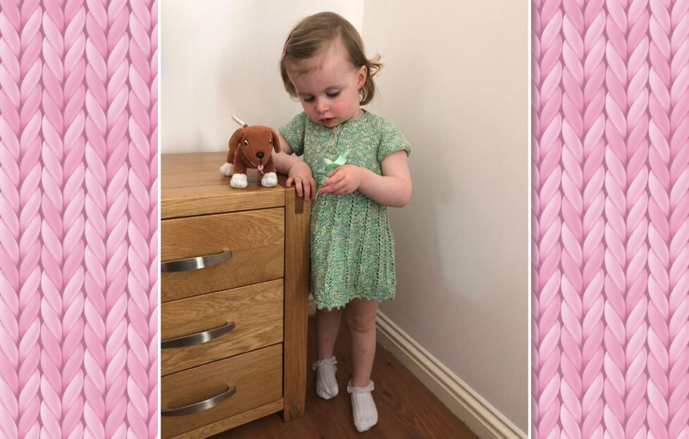 Little toddler modelling green knitted dress with her teddy
