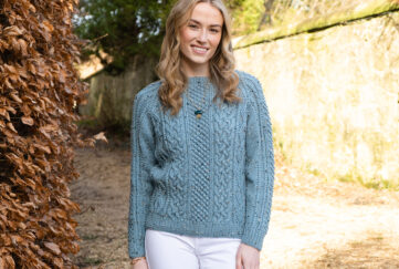 Model wearing knitted Aran sweater in duck egg blue, view of the front