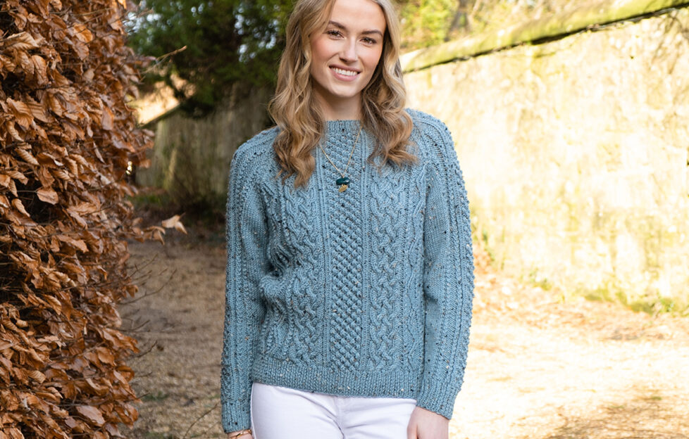 Model wearing knitted Aran sweater in duck egg blue, view of the front