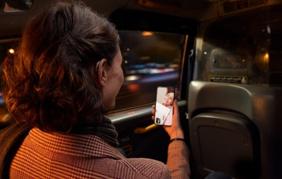Women in car seat talking on video call phone with hearing aid