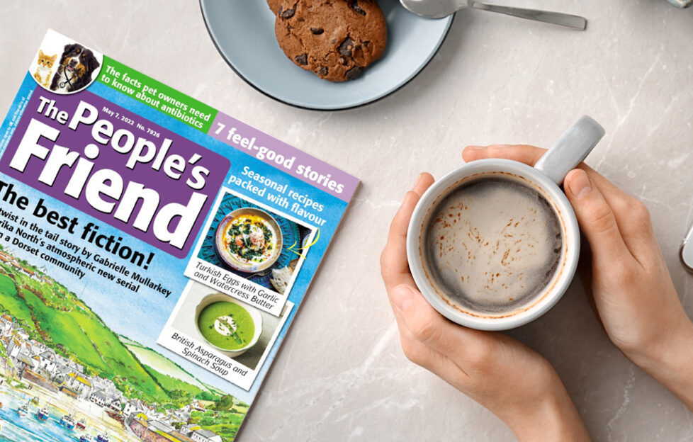 Flatlay of The People's Friend, hands around a coffee and plate of cookies