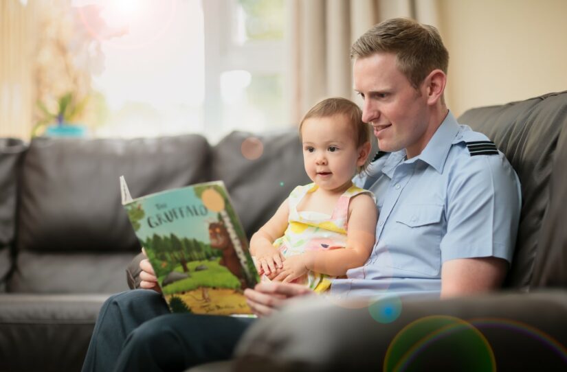 Father reading book to infant on his lap
