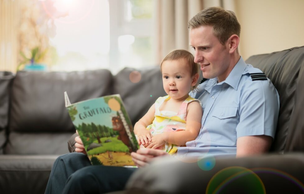 Father reading book to infant on his lap