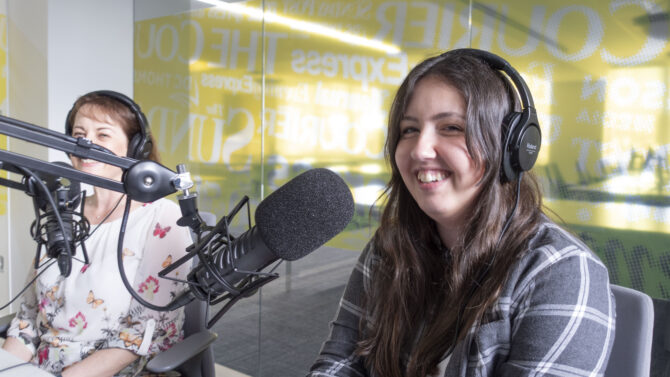 Digital Editor Jacky smiling in podcast studio with microphone and headset