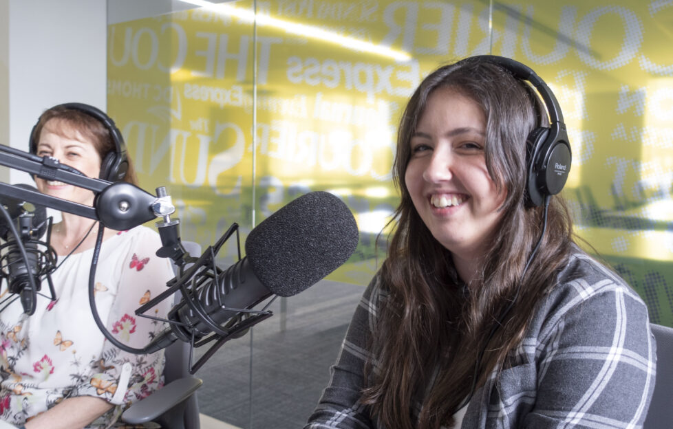 Digital Editor Jacky smiling in podcast studio with microphone and headset