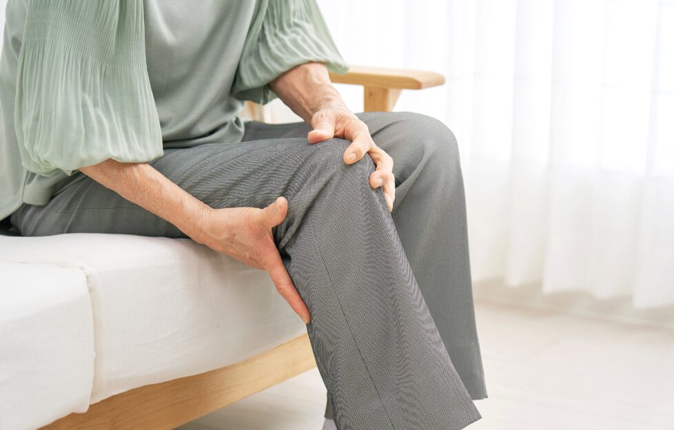 Elderly woman holding knee with aches and pains