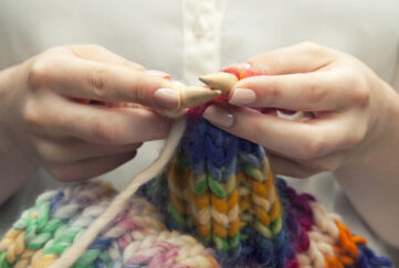 Hands knitting colourful scarf