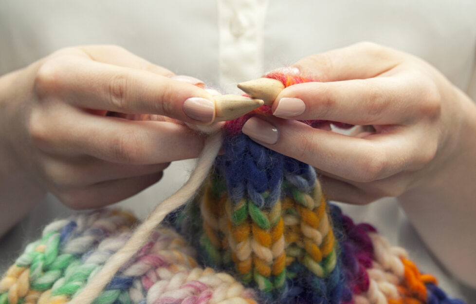 Hands knitting colourful scarf