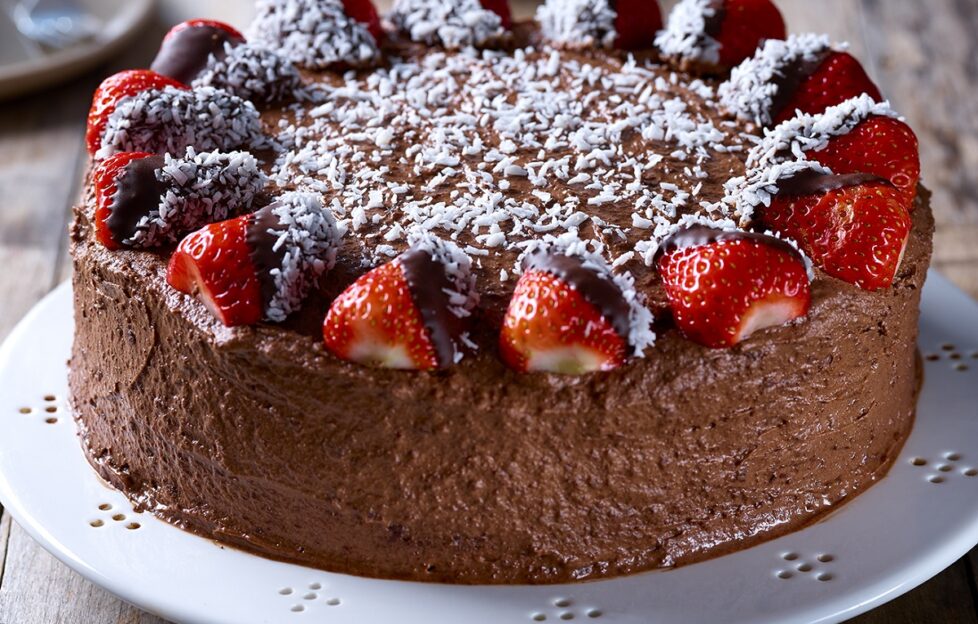 Vegan chocolate and coconut cake decorated with strawberries and icing sugar