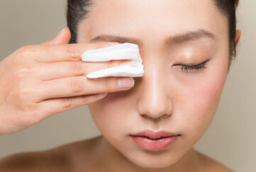 Woman holding cotton pad to her eye