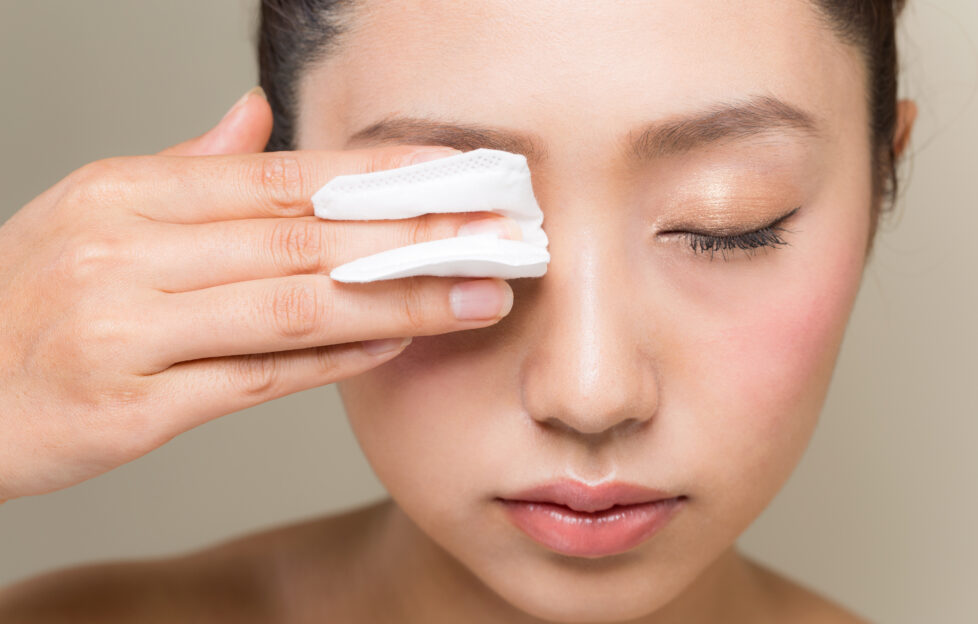 Woman holding cotton pad to her eye
