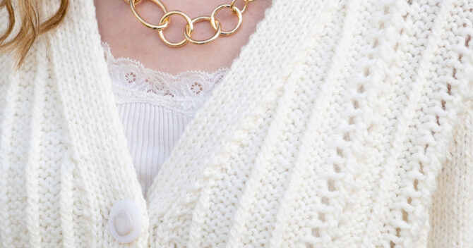 Knitted cream cardigan close up of pattern with gold hooped necklace