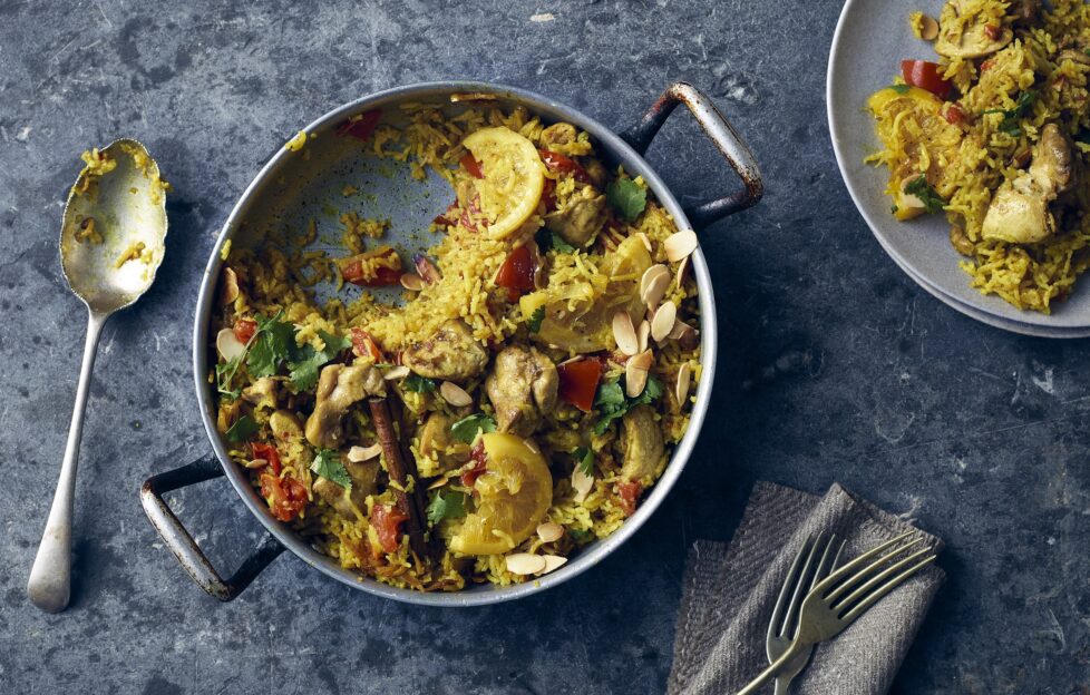 Flatlay of chicken and lemon biryani pot, serving spoon and plated
