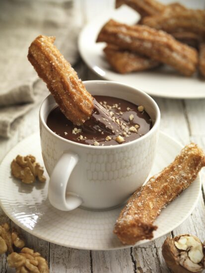 Spanish churros dipped in mug of walnut chocolate