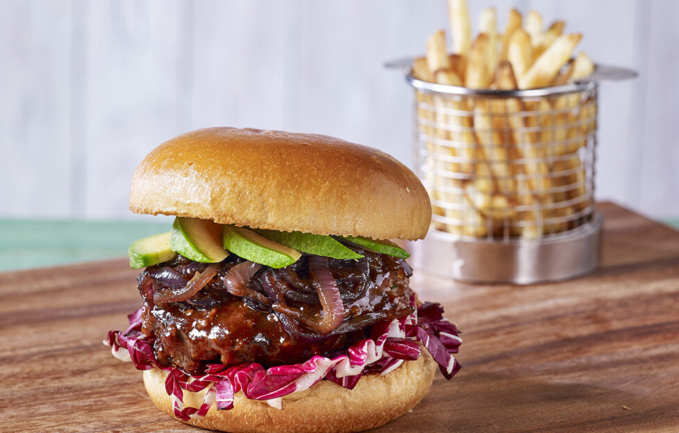 Garlic gourmet burger on table with basket of chips behind