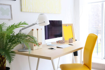 Home office desk with sunshine yellow chair, bright window and house plant