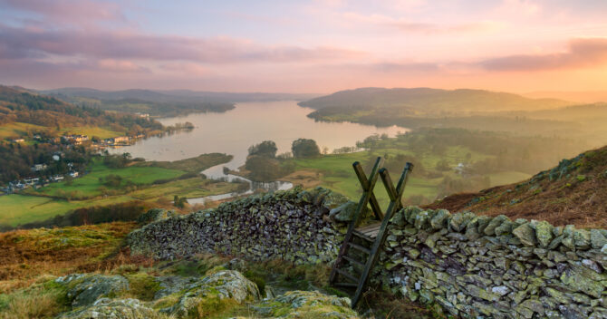 Sunset over Lake Windermere in Lake District. Dry stone wall and step ladder in foreground