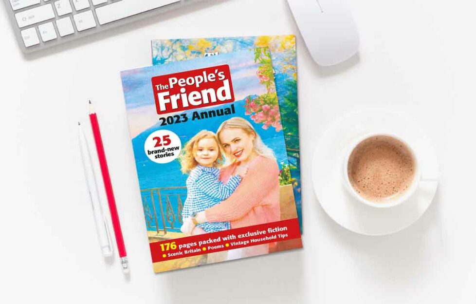 "The People's Friend" 2023 Annual laid on desk with cup of coffee, pencils, mouse and keyboard