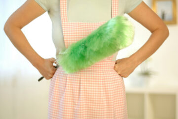 Torso of woman wearing apron and holding feather duster