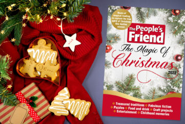 Cover Of The People's Friend Magic Of Christmas bookazine on Christmas flatlay with red blanket, biscuits and present