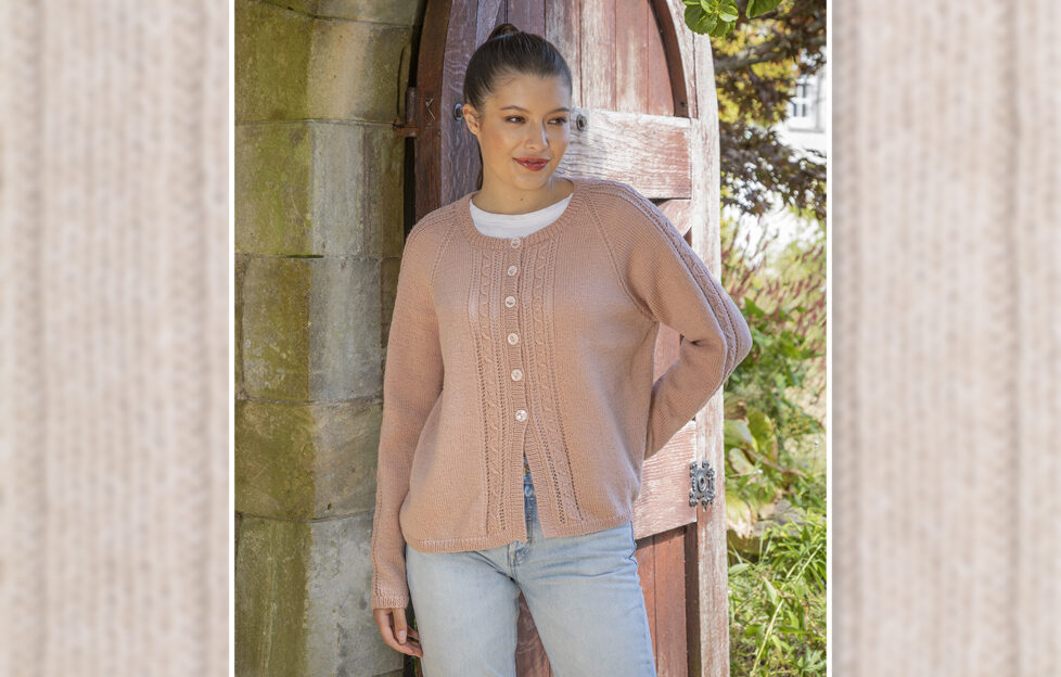 Model with brown hair in front of walled door wearing knitted cardigan