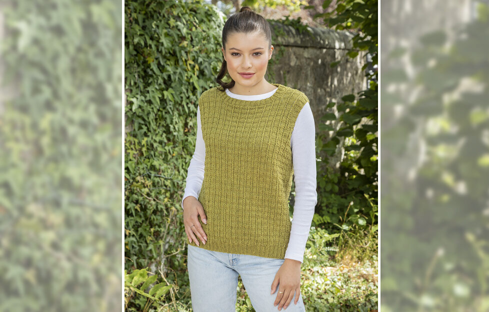 Model wearing knitted tank top in avocado colour with hedges and grass in the background