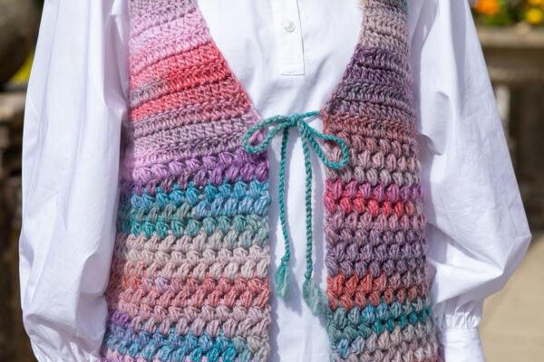 Close up of multicoloured crochet waistcoat over white blouse