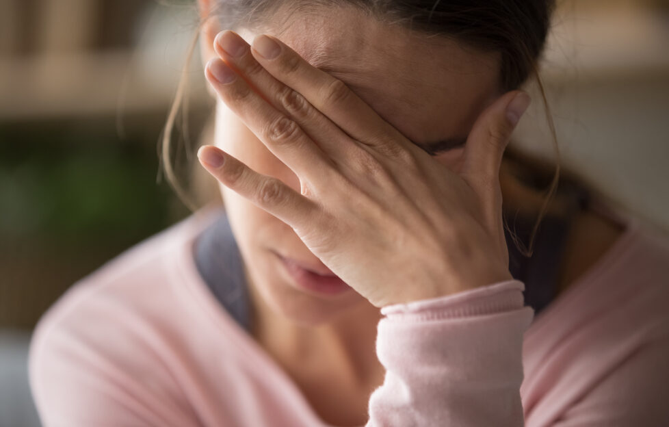 woman holding head in her hand with a headache